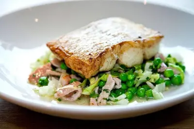 a plate of food with a sandwich and peas at Derby Arms in Longridge