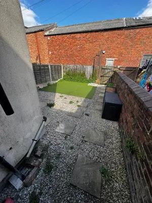 a backyard with a brick wall and a grass yard at Harmony House - Close to Blackpool FC - Excellent Transport Links - Sleeps up to 6 in Blackpool