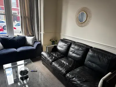 a living room with a black leather couch and a mirror at Harmony House - Close to Blackpool FC - Excellent Transport Links - Sleeps up to 6 in Blackpool
