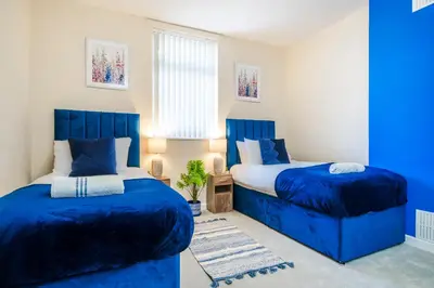 two beds in a bedroom with blue sheets and a blue headboard at Long-Term Work Stay 20 Percent OFF Fully Equipped & Central Location in Horwich