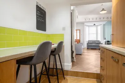 a kitchen with two stools at a counter with green tiles at 10 Min to Beach Cheap Taxi to City FreeParking in Liverpool