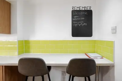 a kitchen with a counter with two chairs and a chalkboard at 10 Min to Beach Cheap Taxi to City FreeParking in Liverpool