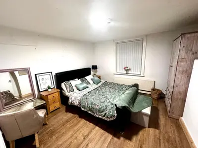 a bedroom with a bed and a dresser and a mirror at Cottage style flat in Oswaldtwistle