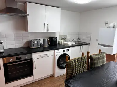a kitchen with white cabinets and a washing machine at Cottage style flat in Oswaldtwistle