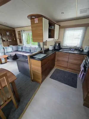 a kitchen with wooden cabinets and a living room at Duck Creek at Beacon Fell View in Longridge