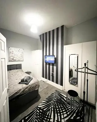 a bedroom with a bed and a mirror at Cozy & Stylish 3-Bed house Parking & 3 Smart TVs in Liverpool