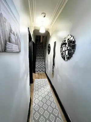a hallway with two paintings on the wall and a stairway at Cozy & Stylish 3-Bed house Parking & 3 Smart TVs in Liverpool