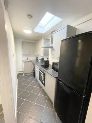 a kitchen with a black refrigerator and white cabinets at Cute two bedroom house with free street parking in Liverpool