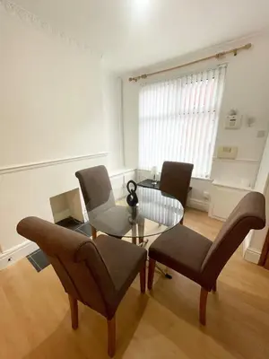 a living room with a glass table and chairs at Cute two bedroom house with free street parking in Liverpool