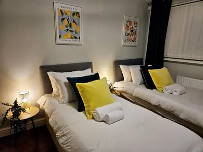 two beds in a room with yellow and white pillows at Platt House in Wigan