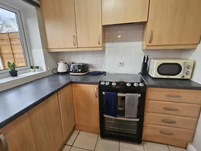 a kitchen with a stove and a microwave at Platt House in Wigan