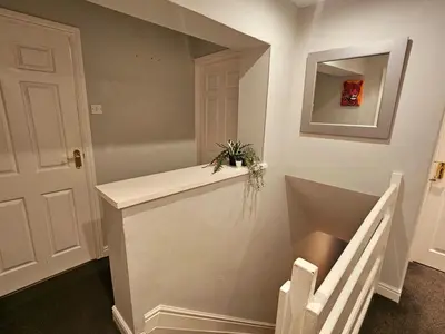 a room with a staircase with a mirror and a plant at Platt House in Wigan