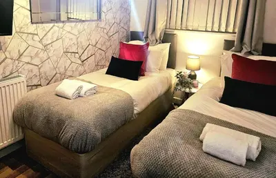 a bedroom with two beds with pillows at Platt House in Wigan