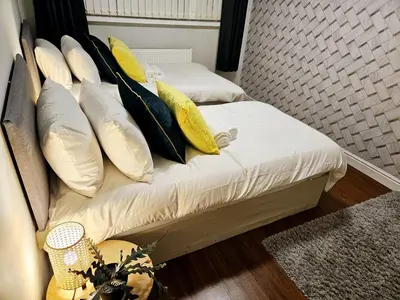 two beds with yellow and white pillows in a room at Platt House in Wigan