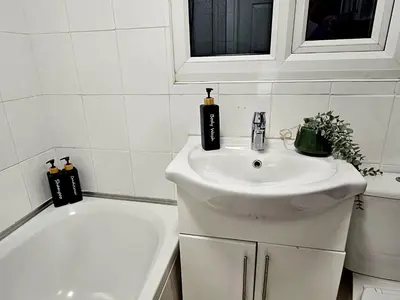 a white bathroom with a sink and a bath tub at Platt House in Wigan