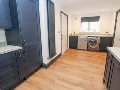 a kitchen with blue cabinets and a washer and dryer at The Alhambra in Southport