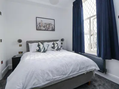 a bedroom with a bed with blue curtains and a window at The Alhambra in Southport
