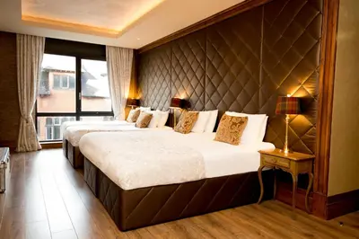 two beds in a hotel room with a padded wall at The Shankly Hotel in Liverpool