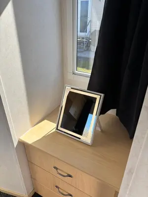a mirror sitting on top of a dresser next to a window at 148 Port Haverigg in Millom