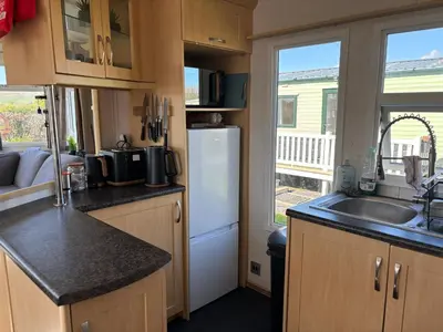 a kitchen with a white refrigerator and a sink at 148 Port Haverigg in Millom
