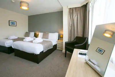 a hotel room with two beds and a desk at The Auckland Hotel in Morecambe