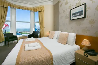 a bedroom with a large bed with a large window at The Auckland Hotel in Morecambe