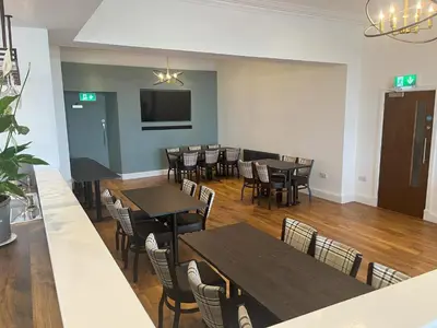 a dining room with tables and chairs and a flat screen tv at The Auckland Hotel in Morecambe