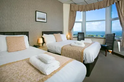 a hotel room with two beds and a large window at The Auckland Hotel in Morecambe