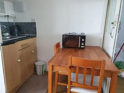 a small kitchen with a wooden table with a microwave at Second or Top Floor Studio Flat in Blackpool