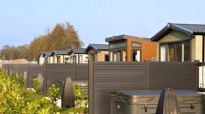 a fence in front of a row of houses at Riverside Holiday Park in Banks