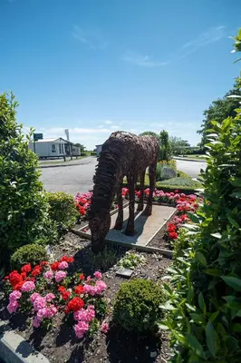 a statue of a giraffe in a garden of flowers at Riverside Holiday Park in Banks