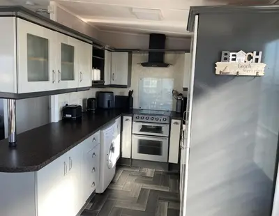 a kitchen with white cabinets and black counter tops at The Dean's on the Lune in Heysham
