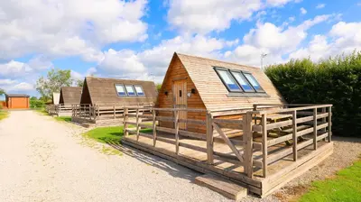 a couple of log homes on a dirt road at Royal Umpire Caravan Park in Croston