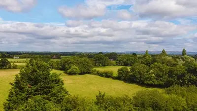 an overhead view of a green field with trees at Royal Umpire Caravan Park in Croston