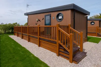 a house with a large deck and a fence at Royal Umpire Caravan Park in Croston