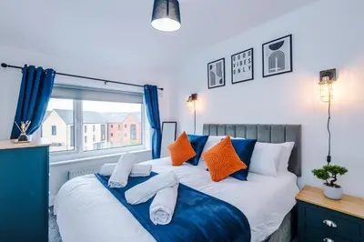 a bedroom with a bed with blue and orange pillows at Acacia Lodge Retreat - Beautiful & Modern 3-BR with Wi-Fi by Parydise Properties in Shevington