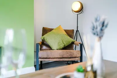 a brown chair with a green pillow on it at Acacia Lodge Retreat - Beautiful & Modern 3-BR with Wi-Fi by Parydise Properties in Shevington