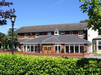 a large red building with a black roof at Briars Hall Hotel in Burscough