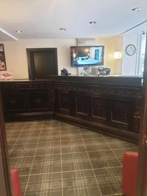 a lobby with a bar with a flat screen tv at Briars Hall Hotel in Burscough