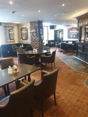 a restaurant with tables and chairs and a bar at Briars Hall Hotel in Burscough