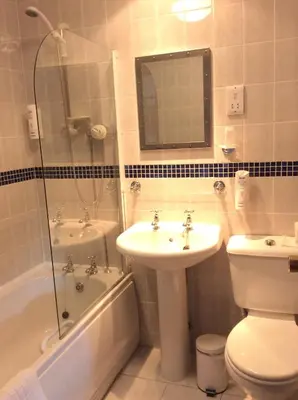 a bathroom with a sink and a toilet and a tub at Briars Hall Hotel in Burscough