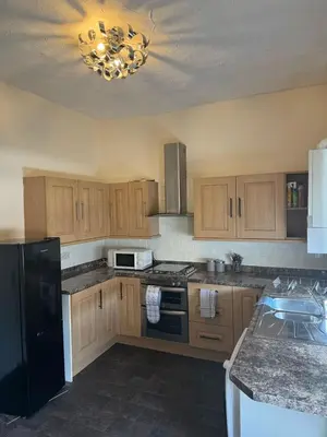 a kitchen with wooden cabinets and a black refrigerator at Comfort, Convenience & Style in Preston