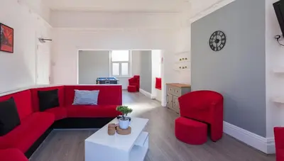 a living room with a red couch and two chairs at Entire Manor Grove Blackpool in Blackpool