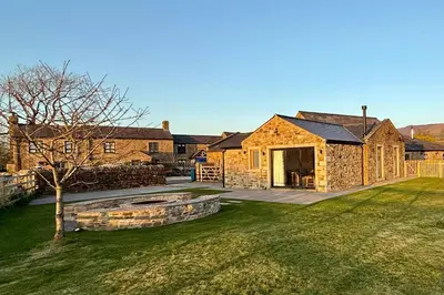 a stone house with a fire pit in the yard at Ribble Valley Hideaways in Preston