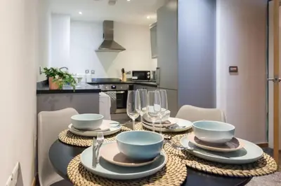 a dining room table with plates and bowls and wine glasses at Elegant City Retreat Contemporary 2BR 2BA Netflix Included in Liverpool