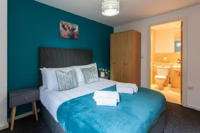 a blue bedroom with a bed with towels on it at Elegant City Retreat Contemporary 2BR 2BA Netflix Included in Liverpool