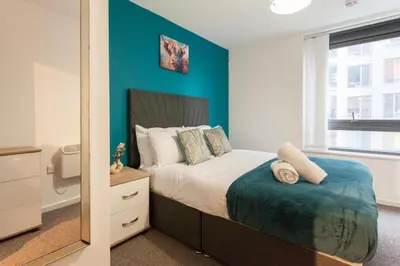 a bedroom with a bed with a blue wall at Prime City Centre Living Large 2 Bed 2 Bath Free Netflix Sleeps 7 in Liverpool