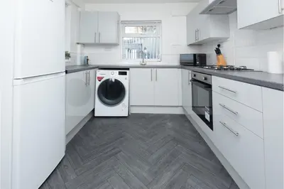 a white kitchen with a washer and dryer in it at Anfield Escape in Liverpool
