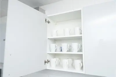 a cupboard filled with white mugs at Anfield Escape in Liverpool