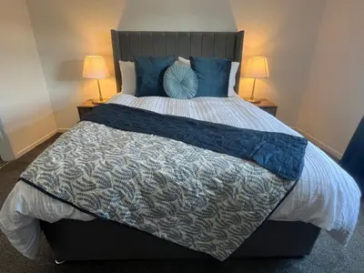 a bedroom with a large bed with blue pillows at Comfy and Connected Standish Home - Two Mins from M6 Jct-27 in Standish